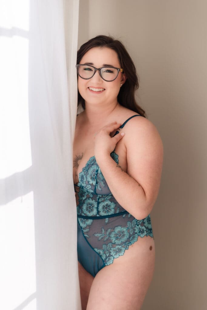 woman in beautiful floral lingerie plays in curtains during knoxville boudoir photography session