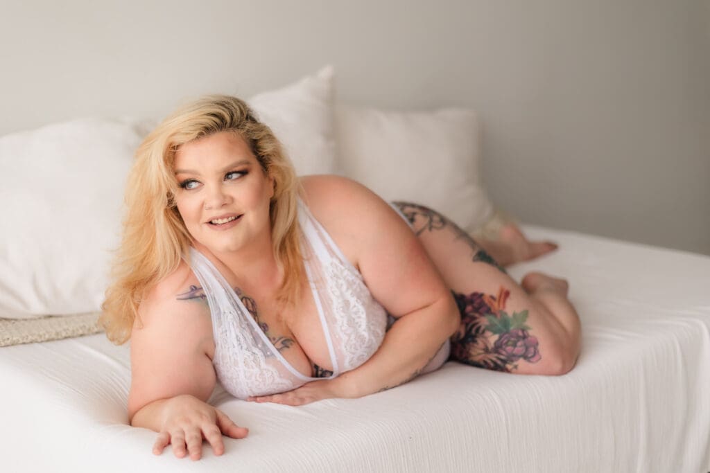 plus size woman laying on bed in white bridal lingerie during knoxville boudoir photography photo session