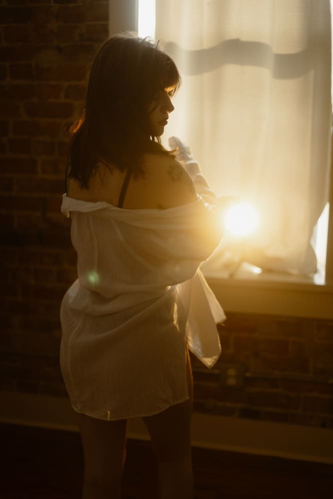 woman wrapped in white flowy shirt during golden hour boudoir session at the lightfoot studio in knoxville